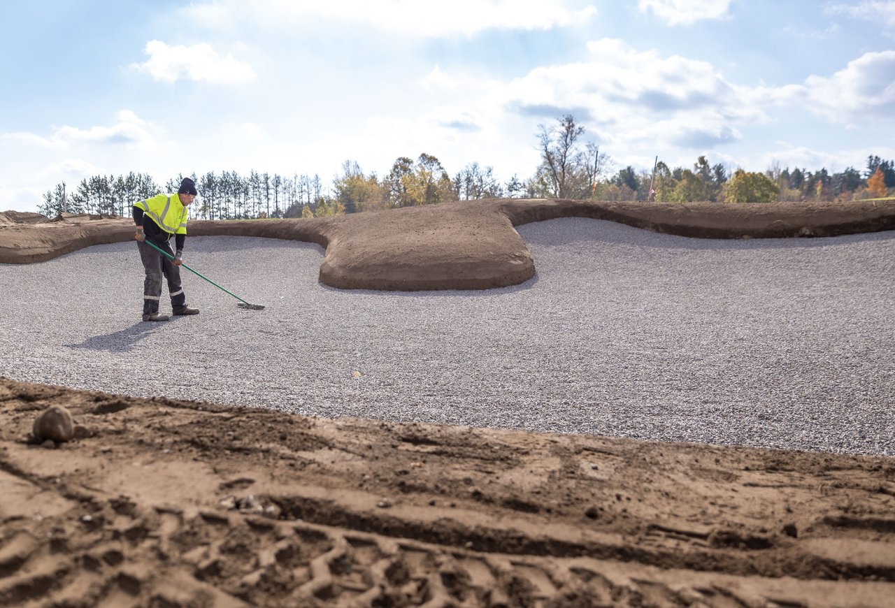 Worker raking the bunker.